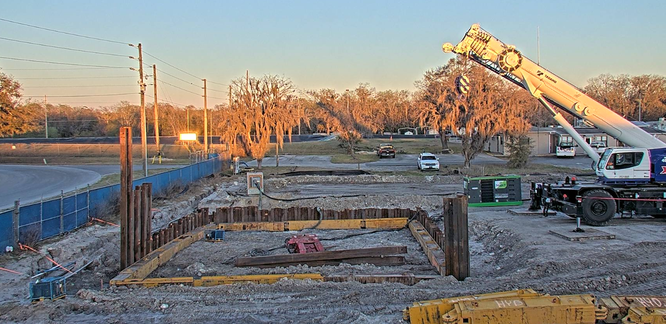 Overview of a shored excavation with crane support at a job site